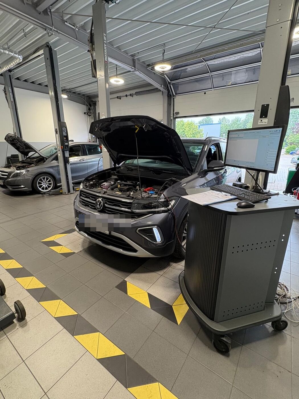 Helle Werkstatthalle von Auto Horn mit mehreren Fahrzeugen an Prüfstation und Hebebühnen